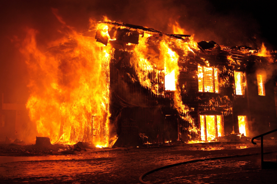 Prédio em chamas durante incêndio de grandes proporções, destacando a importância de sistemas de alarme de incêndio
