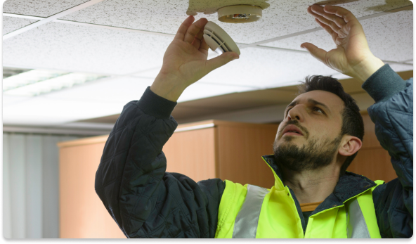 Técnico de segurança instalando detector de fumaça