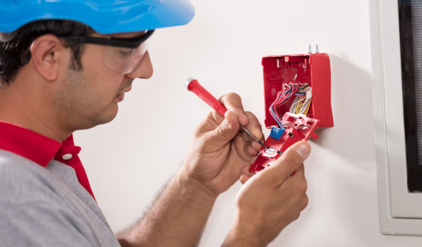 Técnico instalando módulo de alarme e acionador manual como parte da execução do Projeto de Combate a Incêndio