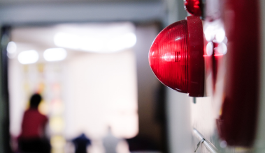 Alarme visual de incêndio instalado em ambiente corporativo, indicando sistema ativo e sinalização de emergência.